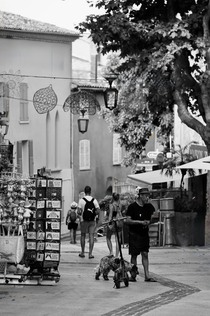 Monochrome image capturing a quaint European village street with people and picturesque architecture.
