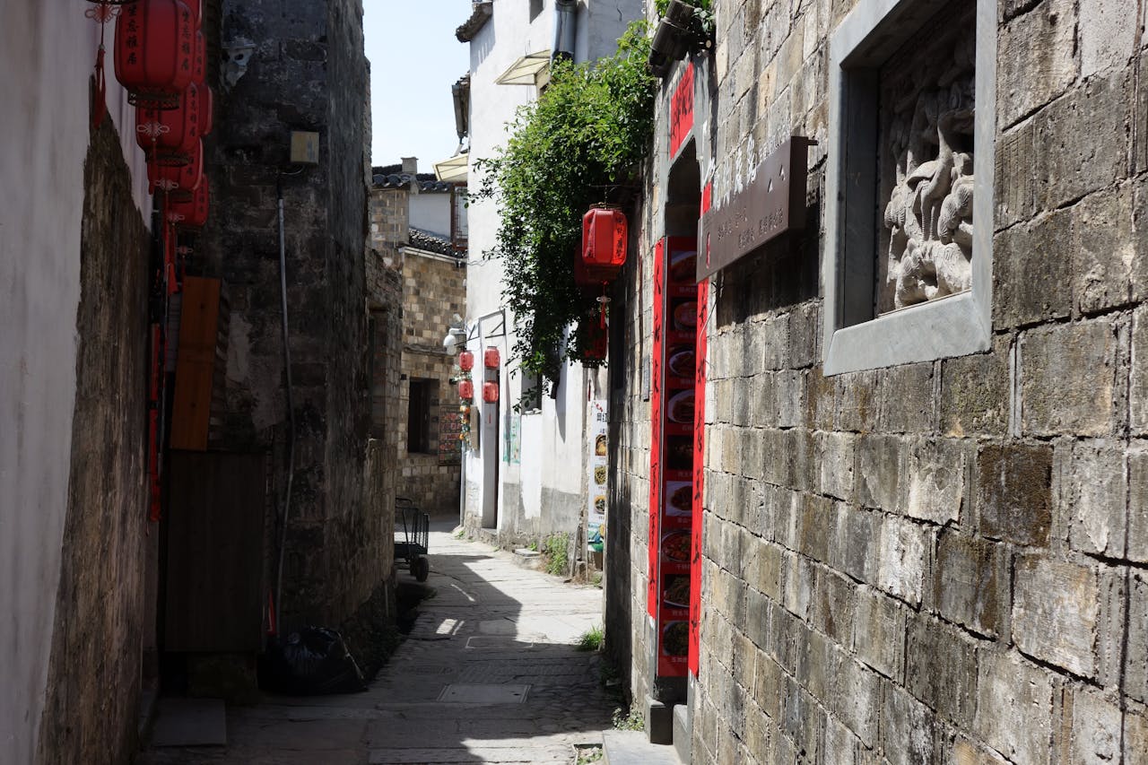 Charming narrow alleyway adorned with red lanterns in an old Asian town.