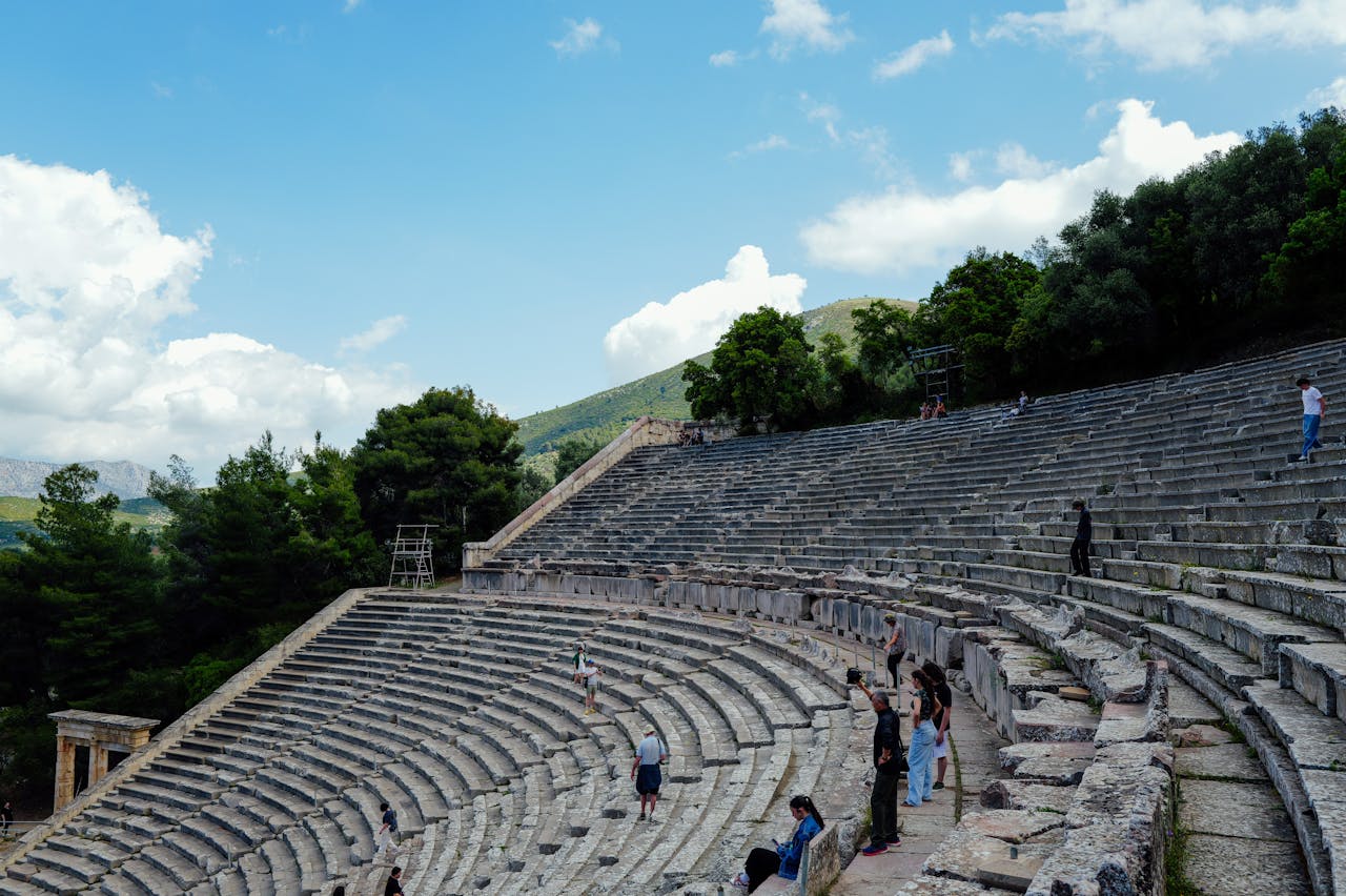 View of the Ancient Theater of Epidaurus with tourists wandering and capturing photos.